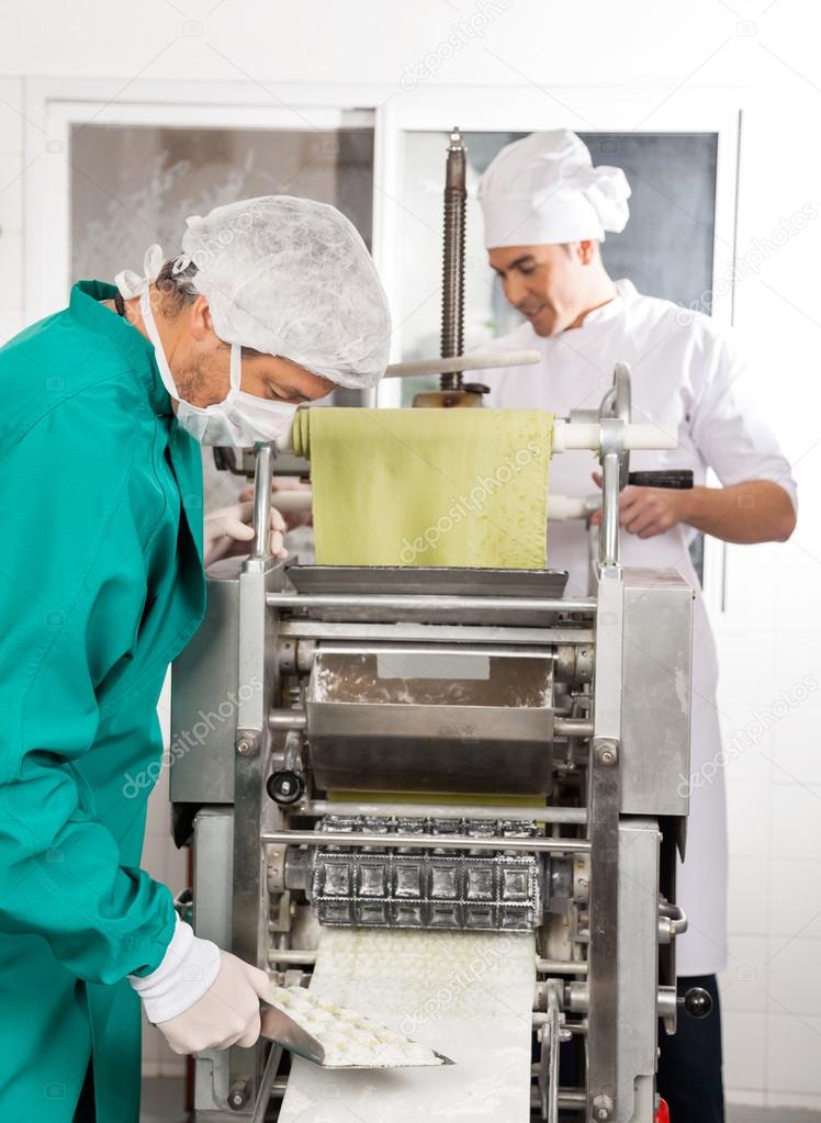 Chefs Processing Ravioli Pasta In Machine