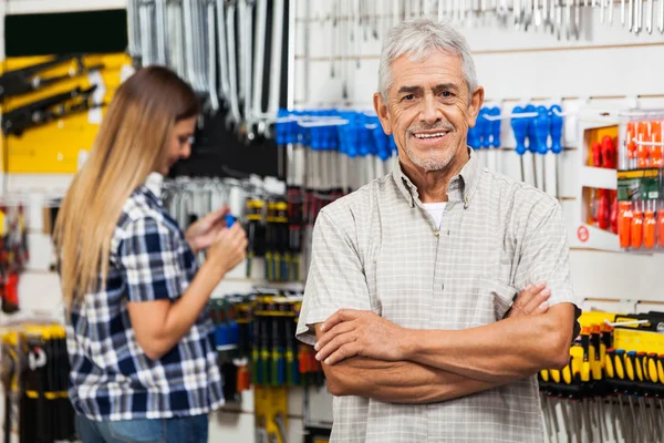 Hombre mayor de confianza con los brazos cruzados en la tienda de hardware — Foto de Stock