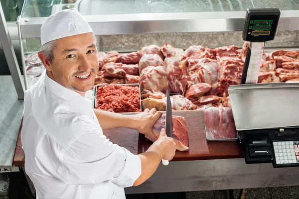 Carnicero cortando carne en el gabinete de exhibición — Foto de Stock