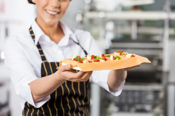 Lächelnder Koch hält Tablett mit gefüllten Ravioli-Nudelblättern — Stockfoto