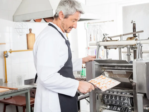 Kucharz mężczyzna wprowadzenie makaron Ravioli w maszynie w kuchni — Zdjęcie stockowe