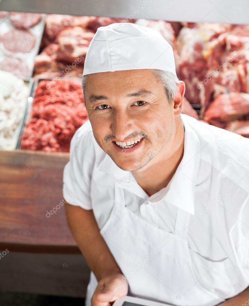 Portrait Of Happy Butcher At Display Cabinet