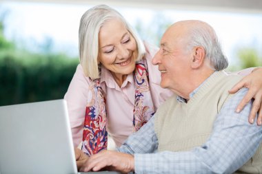 Üst düzey çift birbirine Laptop kullanırken bakarak gülen