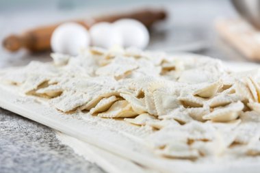 Un ve kesme tahtası üzerinde ham mantı makarna