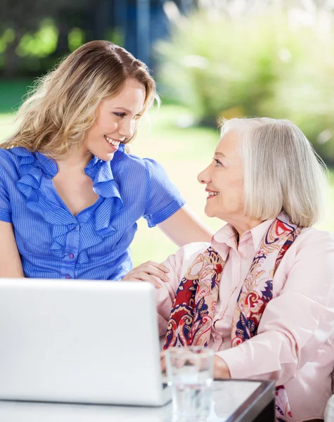 Felice nipote e nonna con computer portatile su portico — Foto Stock