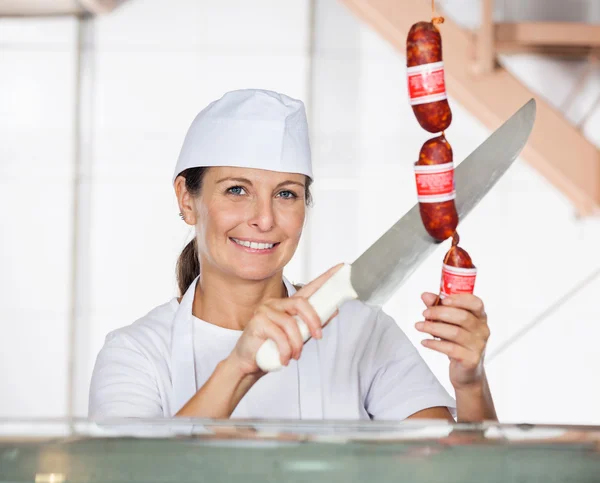 Carniceiro fêmea salsichas de corte em Counter — Fotografia de Stock