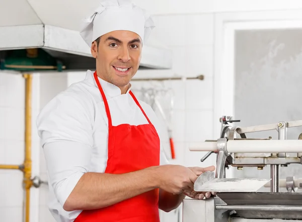 Lächelnder Koch steht neben Ravioli-Nudelmaschine — Stockfoto