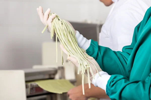 Chef masculino segurando massa de espaguete na cozinha — Fotografia de Stock