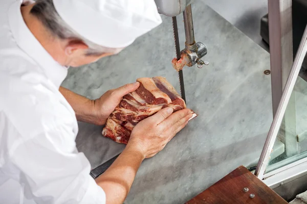 Slaktaren skära köttet med bandsåg — Stockfoto