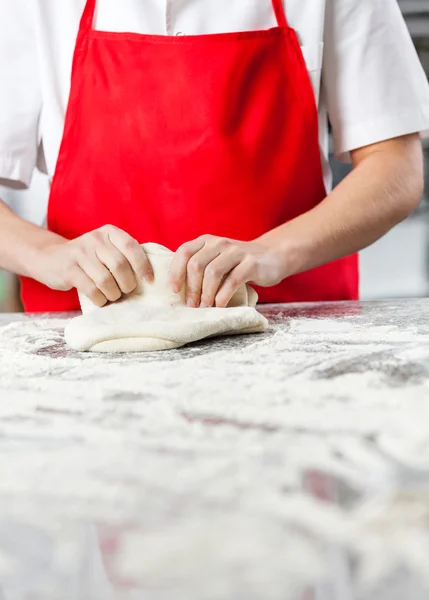 Chef feminino amassando massa em contador bagunçado — Fotografia de Stock