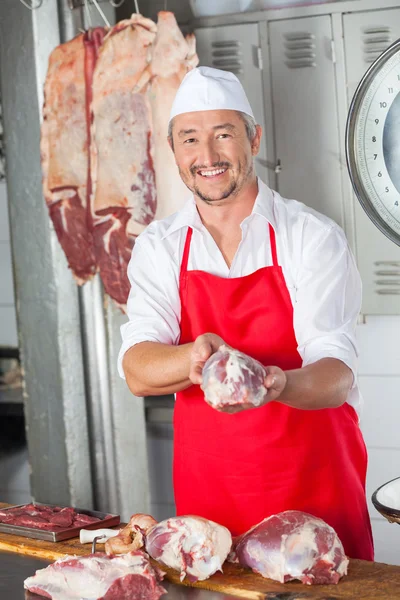 Macellaio maschio sorridente che tiene la carne in macelleria — Foto Stock