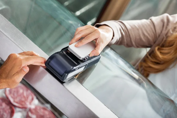 Cliente haciendo el pago a través de Smartphone en la carnicería —  Fotos de Stock