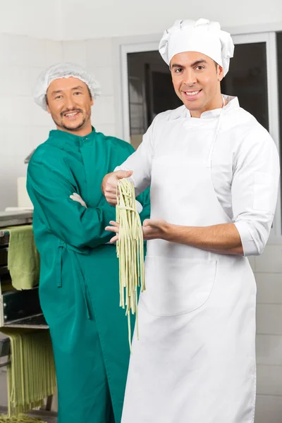 Chefs masculinos confiados con pasta fresca de espaguetis en la cocina — Foto de Stock