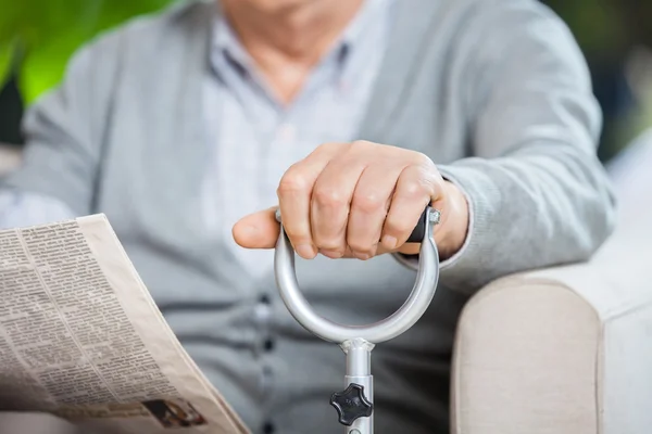 Mittelteil eines älteren Mannes mit Zeitung und Stock — Stockfoto