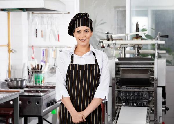 Улыбающаяся шеф-повар, стоящая на кухне — стоковое фото