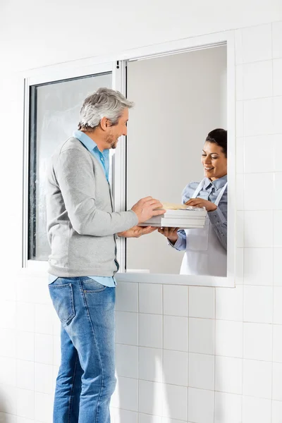 Chef feminino vendendo pacotes de massas para o homem — Fotografia de Stock