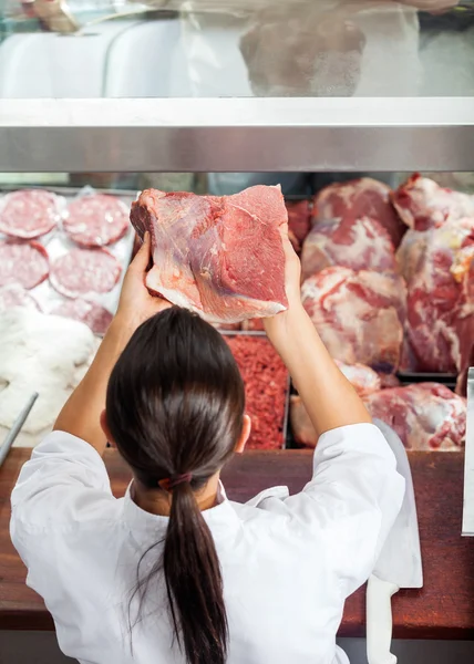 Carnicera sosteniendo carne roja en la carnicería — Foto de Stock