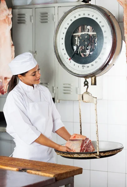 Vrouw met een gewicht van vlees op schaal In slagerij — Stockfoto