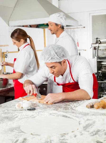 Maschio chef taglio ravioli pasta a contatore in cucina — Foto Stock