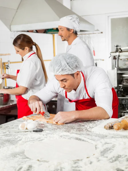 Samec šéfkuchař řezání Ravioli těstoviny na pultu v kuchyni — Stock fotografie