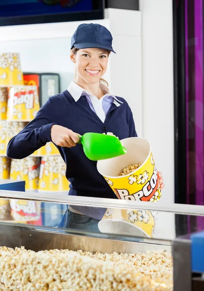 Lavoratore versando popcorn in secchio al cinema concessione stand — Foto Stock