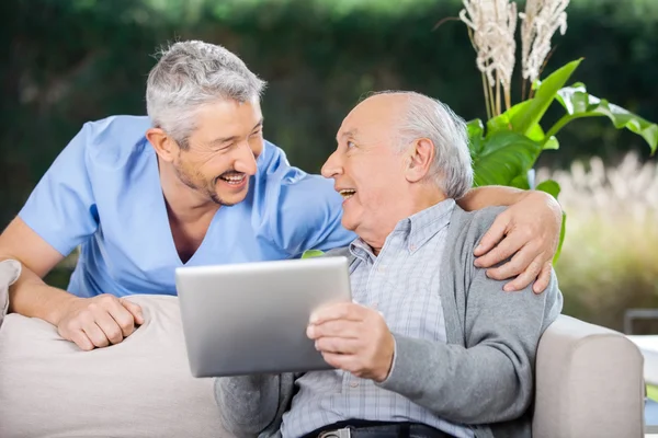 Gardien riant et homme âgé utilisant un ordinateur tablette — Photo