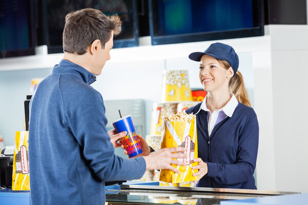 Seller Giving Popcorn And Drink To Man At Concession Stand