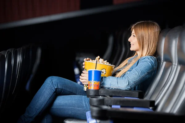 Mujer sosteniendo bocadillos mientras ve películas en el teatro — Foto de Stock