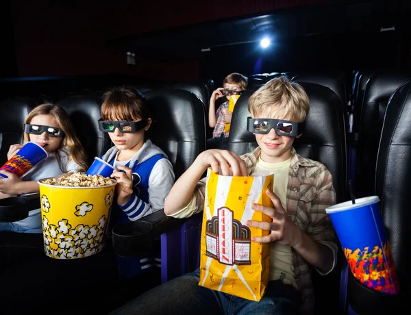 Братья и сёстры, имеющие закуски в 3D кинотеатре — стоковое фото