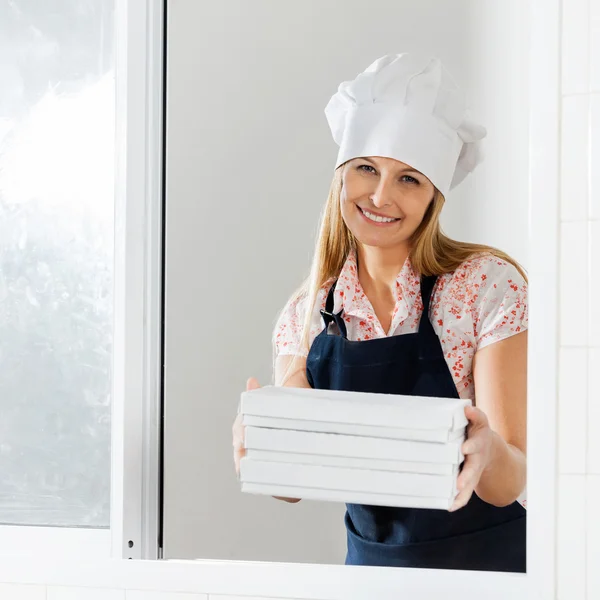 Happy Chef sosteniendo cajas de pasta embaladas en la ventana —  Fotos de Stock