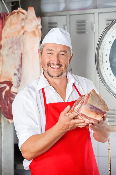 Carniceiro feliz segurando carne na loja — Fotografia de Stock