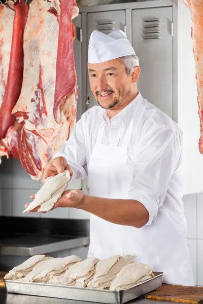 Açougueiro dando pedaços de frango cobertos com farinha — Fotografia de Stock