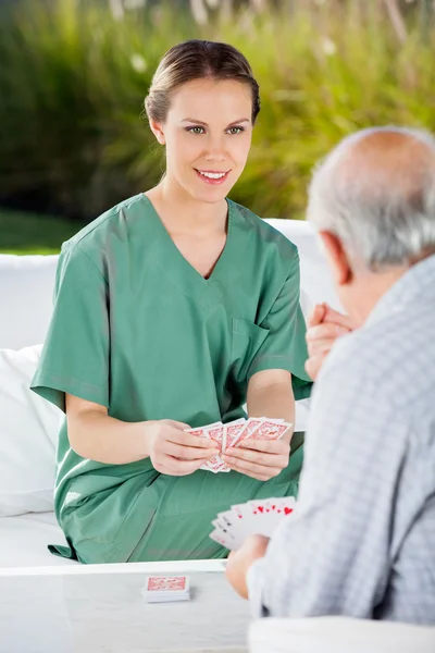 Enfermera jugando a las cartas con un hombre mayor — Foto de Stock