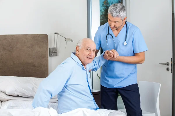 Anziano uomo essere assistito da maschio custode in camera da letto — Foto Stock