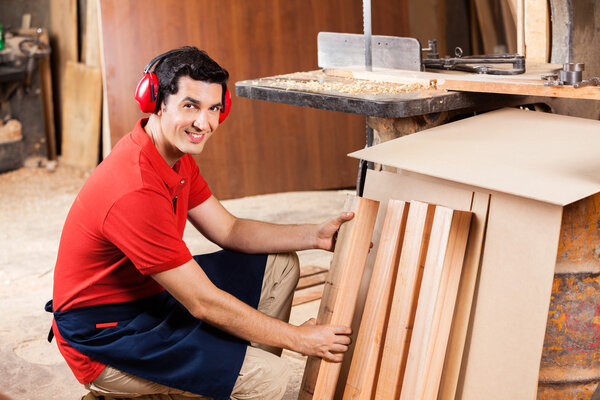 Carpenter Arranging Wooden Planks In Workshop