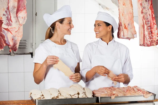 Женщины-мясники держат сырое мясо на прилавке — стоковое фото