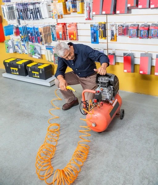 年配の男性が店で空気圧縮機を調べる — ストック写真