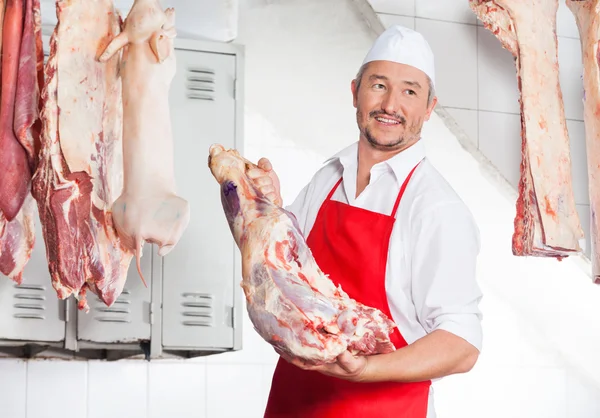 Carnicero sosteniendo carne en la carnicería —  Fotos de Stock