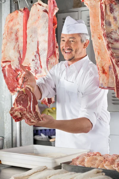 Řezník, dávat syrové maso na přepážce — Stock fotografie