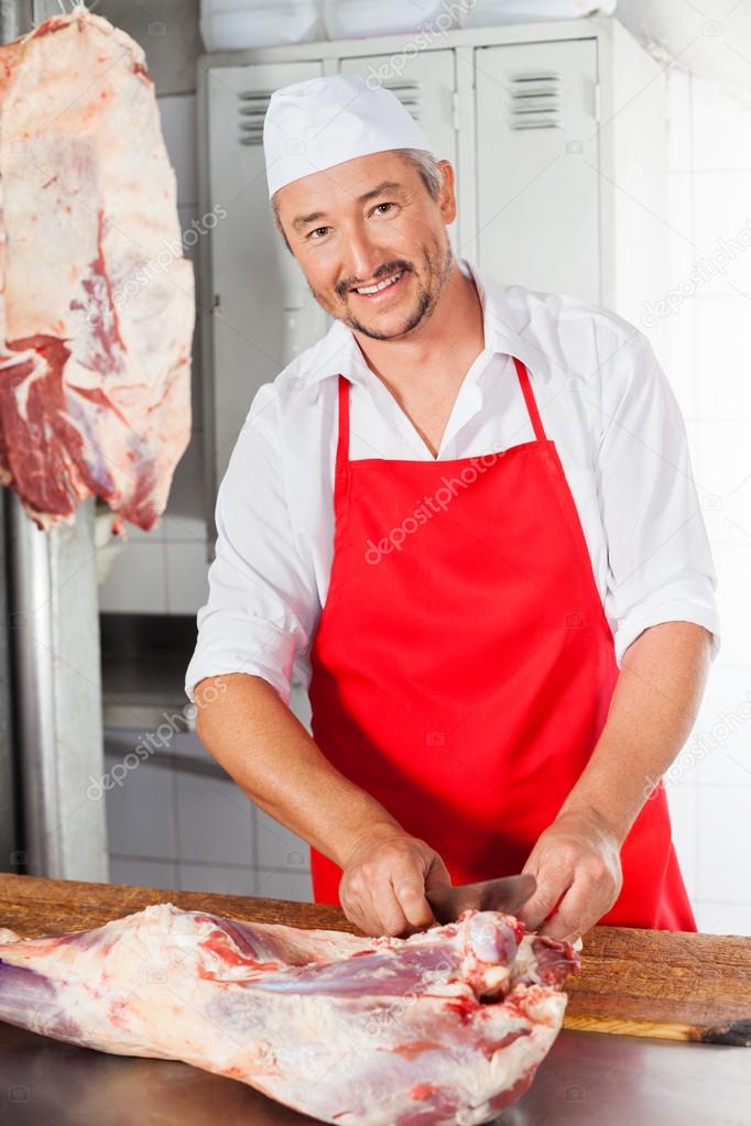Butcher Cutting Meat At Counter In Butchery