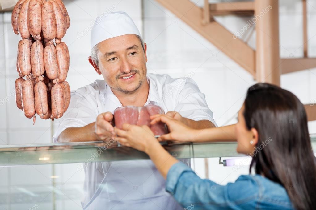 Butcher Giving Pack Of Sausages To Customer