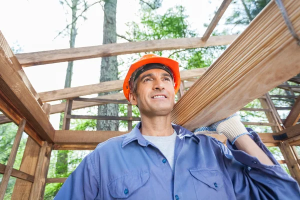 Bauarbeiter trägt Holzbohlen — Stockfoto