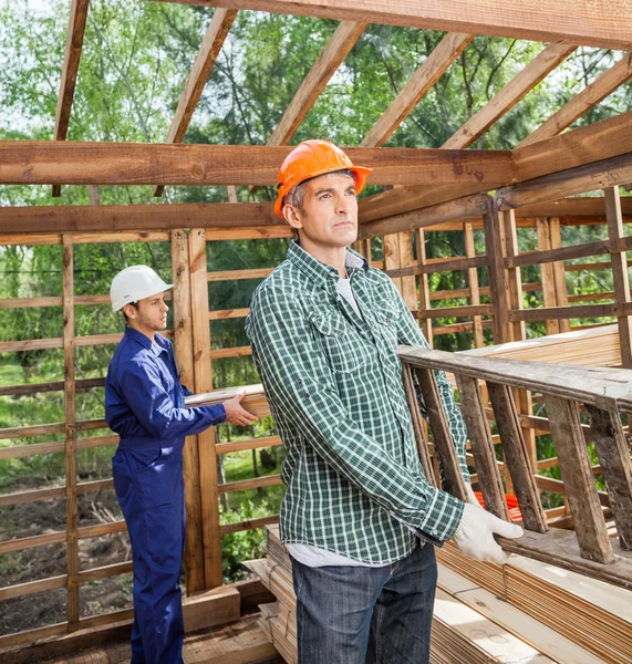 Byggnadsarbetare arbetar i timmer stuga på webbplatsen — Stockfoto