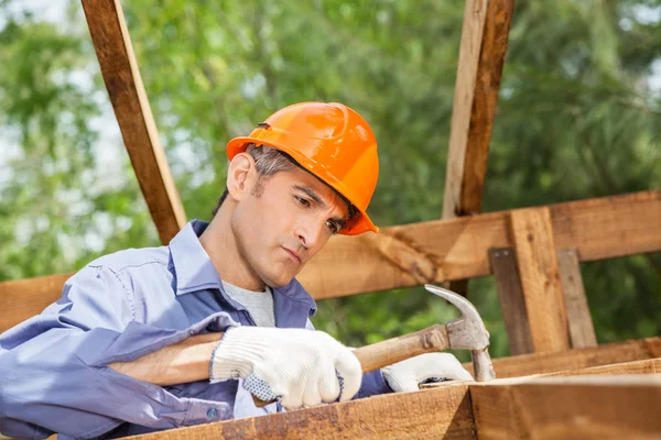Dělník, zatloukání hřebíku na dřevěnou chatu — Stock fotografie