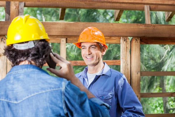 Gelukkig Architect kijken naar collega met behulp van mobiele telefoon — Stockfoto