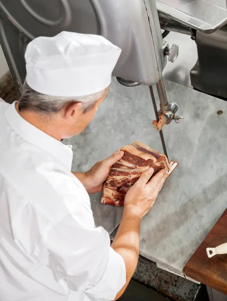Açougueiro cortando carne fresca com serra de fita — Fotografia de Stock