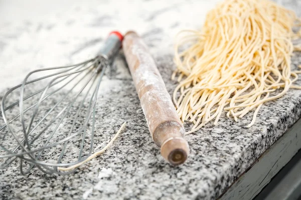 Těstoviny špagety s váleček a šlehací metla na desce — Stock fotografie