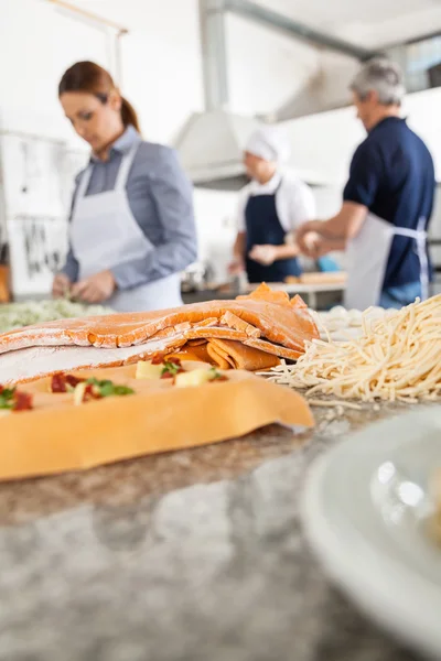 Olika pasta på räknaren med kockar arbetar i bakgrunden — Stockfoto