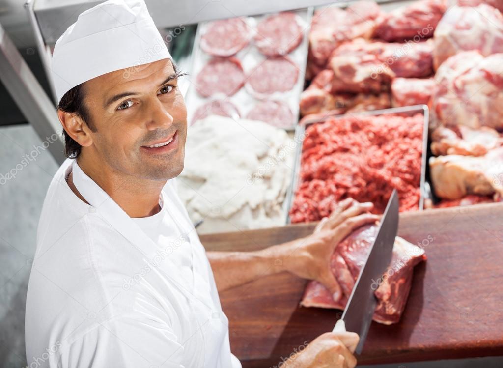 Confident Butcher Cutting Meat At Counter