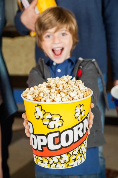 Πορτρέτο του ενθουσιασμένος αγόρι προσφέροντας κουβά ποπ κορν στο σινεμά — Φωτογραφία Αρχείου